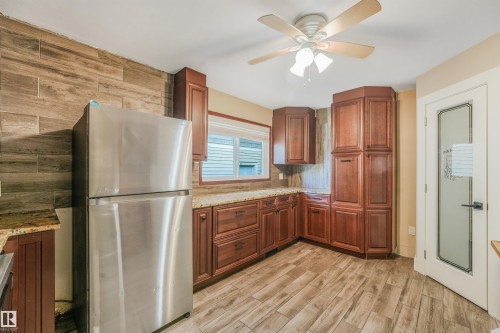 Wood-finish flooring with rich wood cabinetry and light-toned countertops - 9347 105 Avenue Nw, Edmonton, AB 