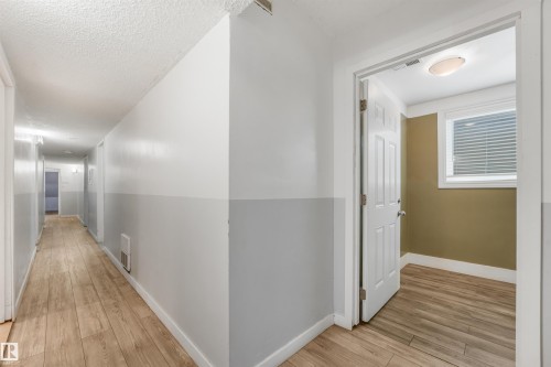 Hallway featuring wood-finish flooring and two-tone wall paint - 9347 105 Avenue Nw, Edmonton, AB 