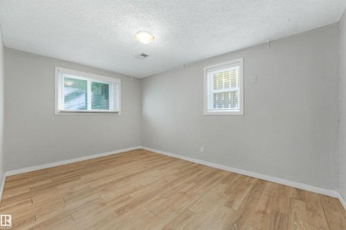 Neutral wall color, wood-finish flooring, two windows with blinds, and ceiling-mounted lighting fixture - 9347 105 Avenue Nw, Edmonton, AB 