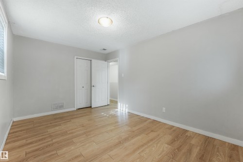 Light wood-finish flooring with neutral wall paint and white trim - 9347 105 Avenue Nw, Edmonton, AB 