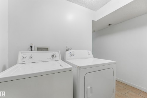 Laundry area featuring a top-load washing machine, front-load dryer, and tile flooring - 9347 105 Avenue Nw, Edmonton, AB 