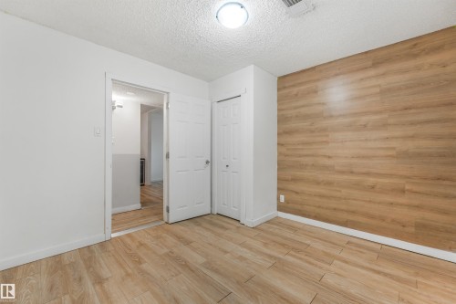 Wood-finish accent wall, wood-finish flooring, recessed lighting, white interior doors, and a built-in closet - 9347 105 Avenue Nw, Edmonton, AB 
