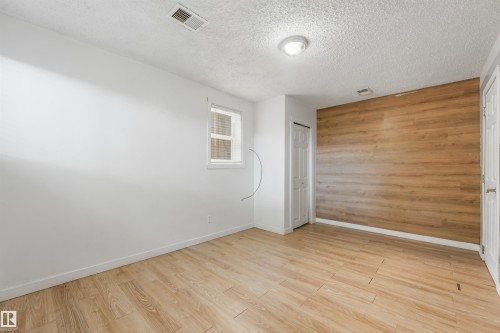 Wood-finish accent wall, wood-finish flooring, white painted walls, white trim, and a window with blinds - 9347 105 Avenue Nw, Edmonton, AB 