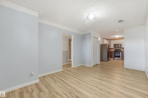 Wood-finish flooring, white trim, recessed lighting, and kitchen with stainless steel appliances - 9347 105 Avenue Nw, Edmonton, AB 