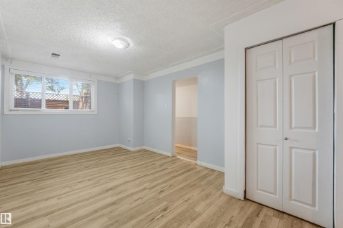 Wood-finish flooring, white bi-fold doors, and a single window with horizontal blinds - 9347 105 Avenue Nw, Edmonton, AB 