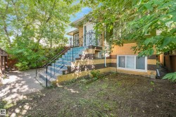 Exterior features brick siding, a concrete staircase with wrought iron railings, and a lower-level window with horizontal blinds - 