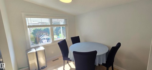 Vaulted ceiling, recessed lighting, large window with blinds, light wood-finish flooring, and white painted walls - 4713 55 Avenue, Vegreville, AB 