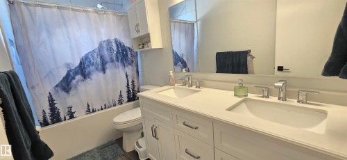 Dual vanity with integrated sinks, white cabinetry, chrome hardware, and a framed mirror - 4713 55 Avenue, Vegreville, AB 