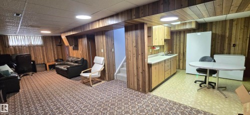 Wood paneling throughout, patterned carpeting, recessed lighting fixtures, built-in cabinetry, and a utility sink - 4713 55 Avenue, Vegreville, AB 