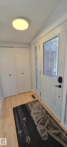 Entryway featuring wood-finish flooring, a white paneled door with decorative glass inlay, and a side light - 4713 55 Avenue, Vegreville, AB 