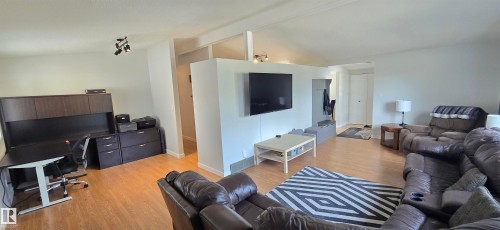 Light wood-finish flooring, recessed lighting, and vaulted ceilings define this open living space - 4713 55 Avenue, Vegreville, AB 