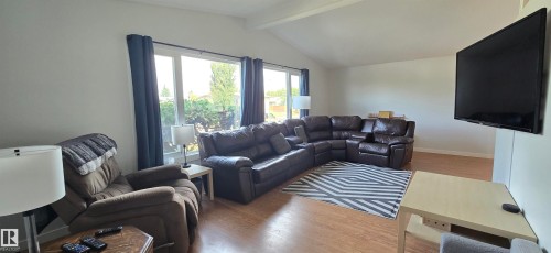 Vaulted ceiling, wood-finish flooring, large picture windows, white walls, and mounted television - 4713 55 Avenue, Vegreville, AB 