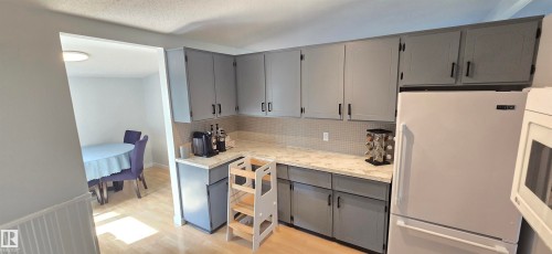 Gray cabinetry with black hardware, light-toned countertops, and a white tile backsplash - 4713 55 Avenue, Vegreville, AB 