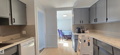 Kitchen featuring gray cabinetry, light-toned countertops, and a tiled backsplash - 4713 55 Avenue, Vegreville, AB 