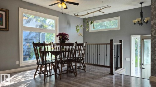 Wood-finish flooring, a ceiling fan with integrated lighting, and a wrought iron chandelier - 5201 56A Street, Beaumont, AB 