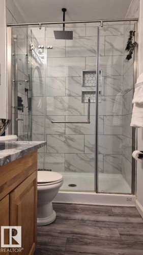 Glass-enclosed shower with a rainfall showerhead and two recessed storage niches - 5201 56A Street, Beaumont, AB 