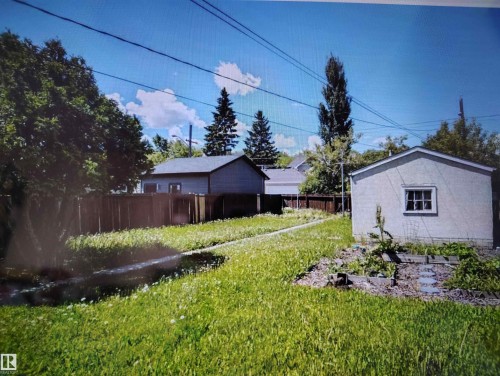 Expansive backyard featuring a detached accessory building, wood fence perimeter, and established trees - 11730 125 Street Nw, Edmonton, AB 