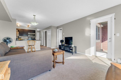 Open-concept living area with neutral carpeting and light gray wall tones - #430 3315 James Mowatt Tr Sw, Edmonton, AB 