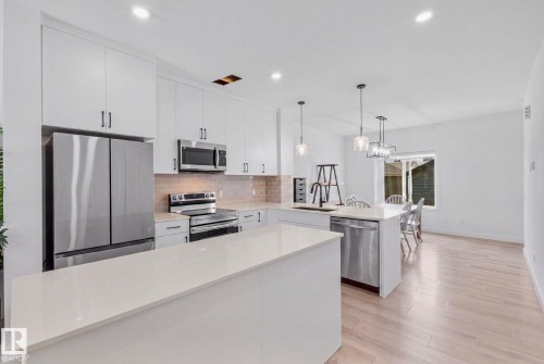 Kitchen featuring white cabinetry, stainless steel appliances, light countertops, a tile backsplash, and recessed lighting - 4023 Hawthorn Link Link Sw, Edmonton, AB 