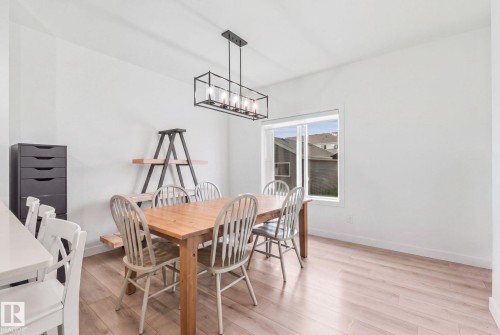 Recessed window with white trim, wood-finish flooring, and a linear chandelier with clear glass panels - 4023 Hawthorn Link Link Sw, Edmonton, AB 