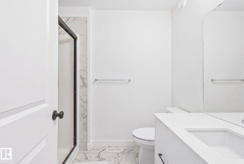 White vanity with integrated sink, sleek black hardware, and a contemporary mirror - 4023 Hawthorn Link Link Sw, Edmonton, AB 