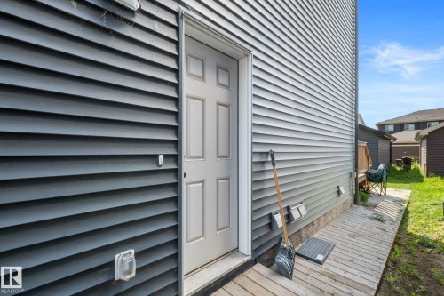 Blue horizontal siding with a white door, and a light wood-finish pathway - 4023 Hawthorn Link Link Sw, Edmonton, AB 
