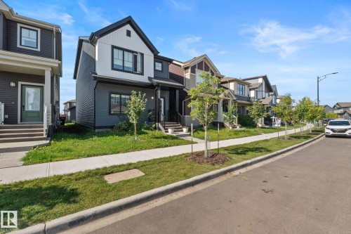 Contemporary exterior with white and dark gray siding, prominent gable roof, and black-framed windows - 4023 Hawthorn Link Link Sw, Edmonton, AB 