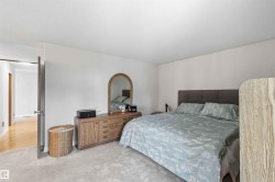 Carpeted bedroom with light-colored walls and a neutral upholstered headboard - 
