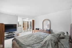 Spacious bedroom featuring light-colored carpeting, white walls, and a flat ceiling - 