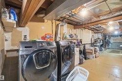Laundry area featuring a side-by-side washer and dryer, exposed ceiling joists, and concrete flooring - 