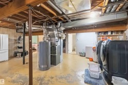 Lower level utility space featuring exposed wood joists and structural beams, a water heater, furnace, and laundry appliances - 