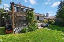 Spacious backyard featuring a wooden deck with railing, mature lawn, and established perimeter fencing - 