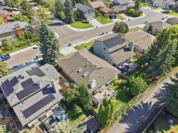 Property featuring a shingle roof, multiple solar panel installations, two skylights, and a chimney - 