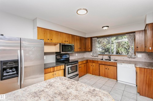 Kitchen featuring wood cabinetry, stainless steel appliances, dual basin sink, and tile flooring - 11440 44A Avenue Nw, Edmonton, AB 