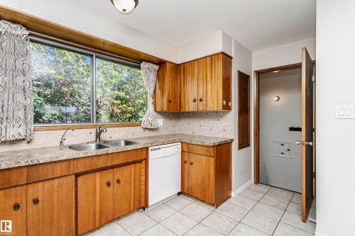 Kitchen featuring wood-finish cabinetry, a double-basin stainless steel sink, a dishwasher, and tiled flooring - 11440 44A Avenue Nw, Edmonton, AB 