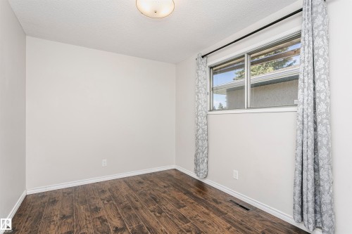 Wood-finish flooring with white baseboards, light neutral wall paint, and a flush mount ceiling light fixture - 11440 44A Avenue Nw, Edmonton, AB 