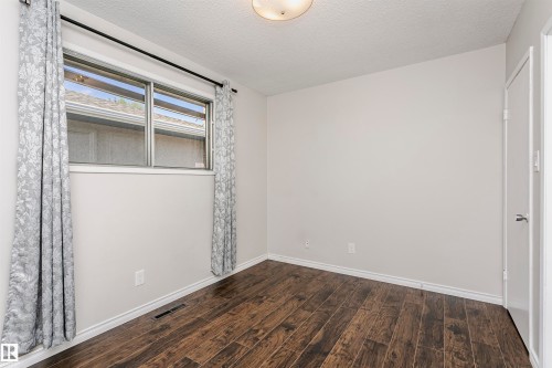 Wood-finish flooring with white baseboards, light neutral wall paint, and a built-in window - 11440 44A Avenue Nw, Edmonton, AB 