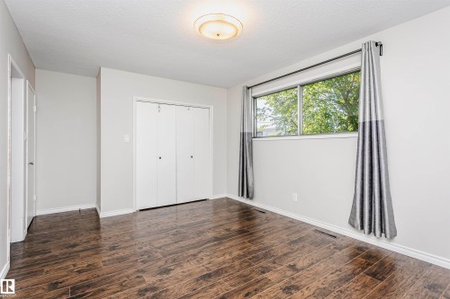 Wood-finish flooring, white walls, and a window with a dark rod - 11440 44A Avenue Nw, Edmonton, AB 