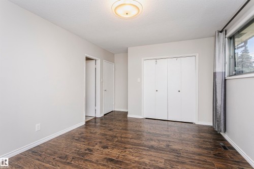 Wood-finish flooring, white walls, white trim, bi-fold closet doors, and an overhead light fixture - 11440 44A Avenue Nw, Edmonton, AB 