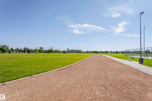 Expansive green space featuring a walking path, paved pathway, and distant athletic courts - 11440 44A Avenue Nw, Edmonton, AB 