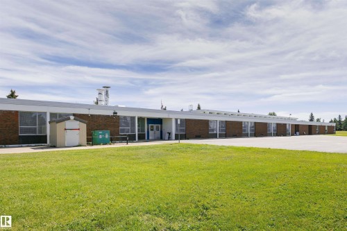 Brick exterior with a flat roofline, multiple windows, and a paved lot - 11440 44A Avenue Nw, Edmonton, AB 