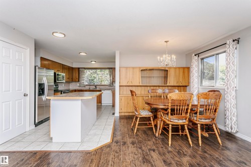 Kitchen with wood cabinetry, stainless steel refrigerator, and central island - 11440 44A Avenue Nw, Edmonton, AB 