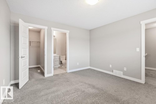 Neutral wall paint, carpet flooring, a walk-in closet, and an attached bathroom with a vanity - 22 Hope Common, Spruce Grove, AB 