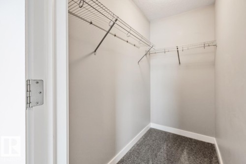 Walk-in closet with wire shelving, light gray walls, white trim, and gray carpet - 22 Hope Common, Spruce Grove, AB 