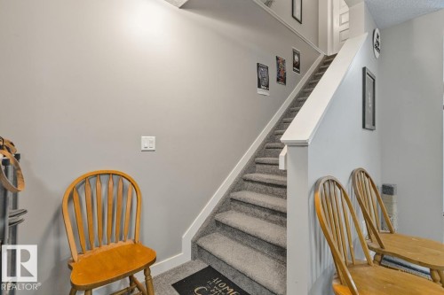 Carpeted staircase with white risers and handrail, featuring light gray wall paint - 22 Hope Common, Spruce Grove, AB 