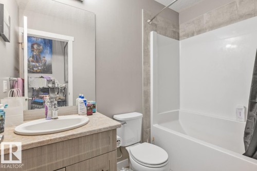 Vanity with a single basin sink, light-toned countertop, and wood-finish cabinetry - 22 Hope Common, Spruce Grove, AB 