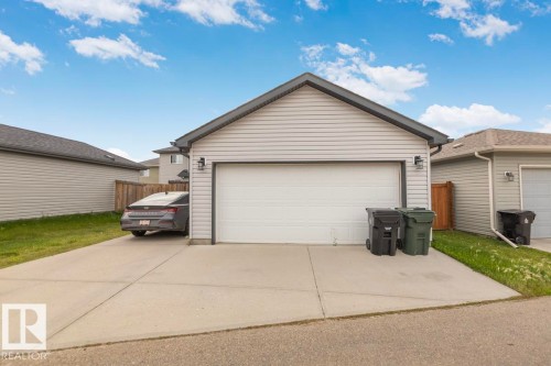 Attached garage featuring horizontal siding and a paved driveway - 22 Hope Common, Spruce Grove, AB 