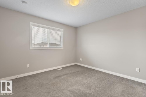 Light gray wall paint, gray carpet flooring, white window trim, horizontal blinds, and a ceiling-mounted light fixture - 22 Hope Common, Spruce Grove, AB 
