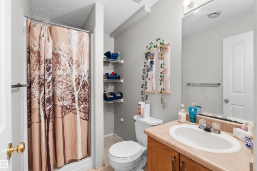 Bathroom featuring a shower stall, a vanity with an integrated sink, a wall-mounted mirror, and wall-mounted shelving - 13028 34 Street Nw, Edmonton, AB 