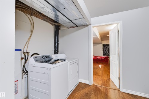 Laundry area with washer and dryer units, featuring a water heater and wood-finish flooring - 13028 34 Street Nw, Edmonton, AB 